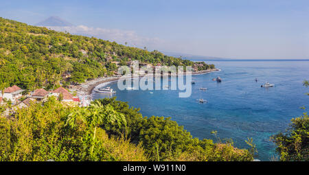 Aerial view of Amed beach in Bali, Indonesia. Traditional fishing boats called jukung on the black sand beach and Mount Agung volcano in the Stock Photo
