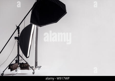 Professional photo studio with light setup included octagon softbox on boom, strip soft box and reflector on light gray background. indoor studio shot Stock Photo