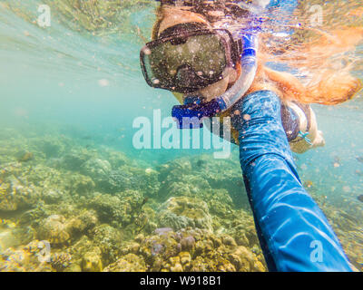 Happy woman in snorkeling mask dive underwater with tropical fishes in coral reef sea pool. Travel lifestyle, water sport outdoor adventure, swimming Stock Photo
