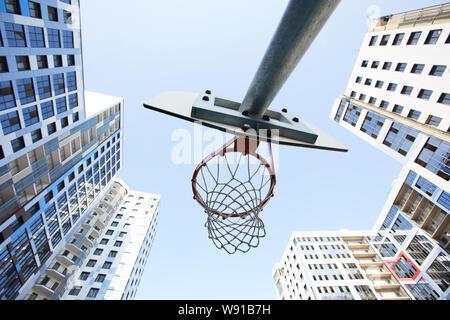 Low angle view at basketball hoop against sky in urban background, copy space Stock Photo