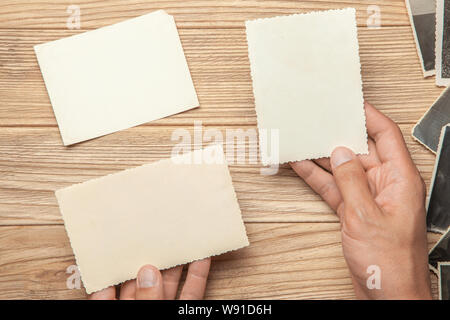 Old photo in the hands of man. Empty template for picture, mock-up. Wooden background Stock Photo