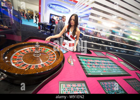 A young woman demonstrates a roulette wheel during the 7th Global Gaming Expo Asia (G2E Asia 2013) in Macau, China, 22 May 2013.   Casino industry lea Stock Photo