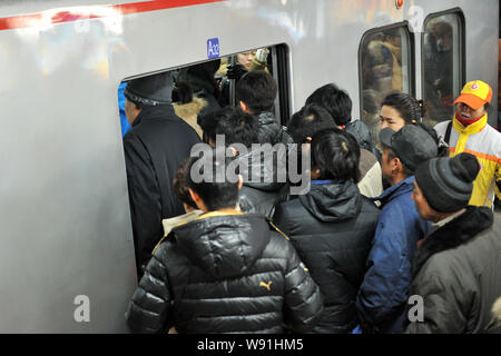 --FILE--A crowd of passengers queue up to enter a metro train at a subway station during the rush hour in Beijing, China, 25 January 2013.   Beijings Stock Photo