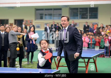 British Prime Minister David Cameron, right, plays table tennis with young Chinese students during his visit to a primary school in Chengdu city, sout Stock Photo