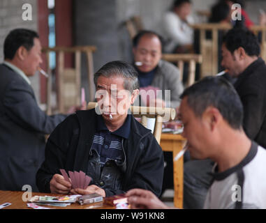 --FILE--Chinese men smoke as they play poker at a teahouse in Lecheng town, southwest Chinas Sichuan province, 14 April 2012.   Chinas government has Stock Photo