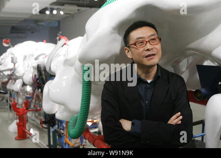 --FILE--Chinese artist Wang Jianwei poses next to one of his artworks ...