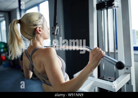 Young woman doing strength training on latley to build muscle for the back Stock Photo