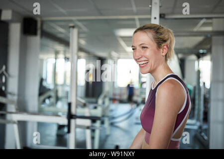 Laughing young woman in the gym has fun while exercising Stock Photo