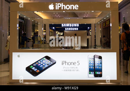 --FILE--Customers walk past an advertisement for iPhone 5 smartphones at a shopping mall in Beijing, China, 5 August 2013.   After years of smartphone Stock Photo