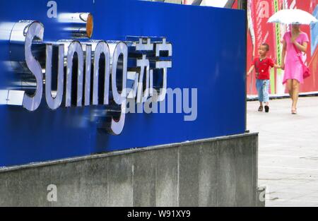 --FILE--Pedestrians walk past a signage of home appliance retailer Suning in Yichang, central Chinas Hubei province, 25 August 2013.   Home appliance Stock Photo
