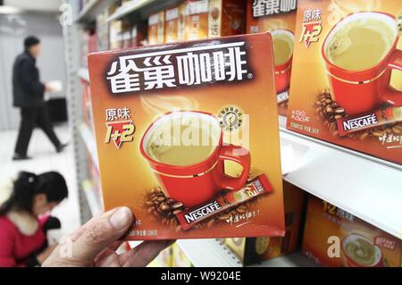 --FILE--A customer buys Nescafe coffee of Nestle at a supermarket in Xuchang city, central Chinas Henan province, 17 March 2013.   Nestle announced pl Stock Photo