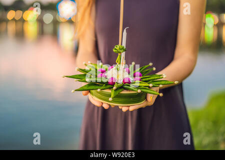 A female tourist holds the Loy Krathong in her hands and is about to launch it into the water. Loy Krathong festival, People buy flowers and candle to Stock Photo