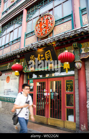Pedestrians walk past a shop of Tongrentang, a time-honored traditional Chinese medicine brand since 1669, in Shanghai, China, 24 May 2013.   Traditio Stock Photo