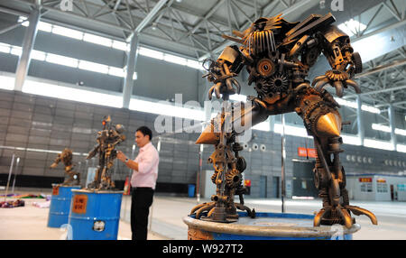 A robot, right, made from auto scraps in the shape of Jetfire, a figure from the movie series, Transformer, is displayed as a Chinese fan examines and Stock Photo