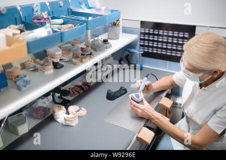 Dental technician working in her office full of equipment. Stock Photo