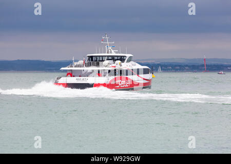 Red Jet ferry, Red Jet 6 ferry, high speed catamaran leaving West Cowes, Isle of Wight for Southampton, Hampshire, UK in August under stormy skies Stock Photo