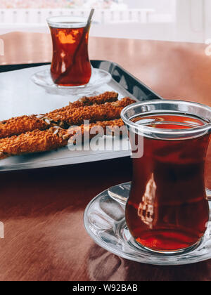 Turkish tea Close-up photo Two traditional Turkish glasses with hot tea and sesame cookies stand on an old wooden table Stock Photo