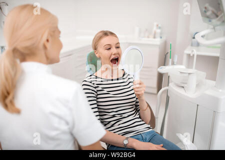 Dentists patient looking at her teeth in the mirror. Stock Photo