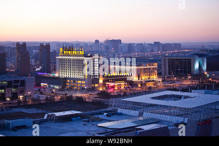 --FILE--Cars pass by new residential apartment buildings along a nearly empty street in Kangbashi district, Ordos city, north Chinas Inner Mongolia Au Stock Photo