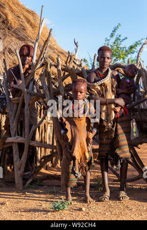 Turmi, Omo River Valley, Ethiopia - May 10, 2019: Portrait of a Hamar womand and children in village. The Hamer are a primitive tribe and the women ha Stock Photo