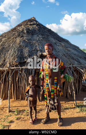 Turmi, Omo River Valley, Ethiopia - May 10, 2019: Portrait of a Hamar woman and children in village. The Hamer are a primitive tribe and the women hav Stock Photo