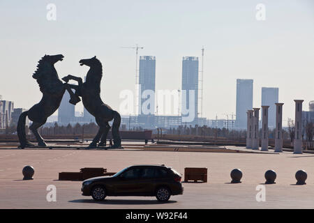 --FILE--A car passes by horse sculptures on the square in Kangbashi district, Ordos city, north Chinas Inner Mongolia Autonomous Region, 16 December 2 Stock Photo