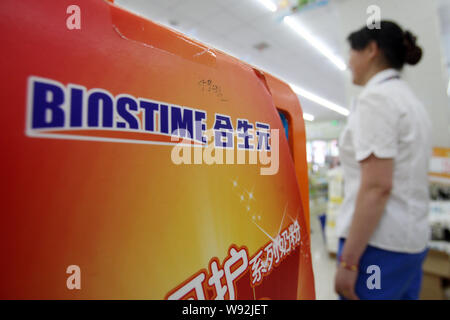 --FILE--A Chinese employee walks past an advertisement of Biostime formula at a supermarket in Shanghai, China, 10 July 2013.   Chinese competitors of Stock Photo