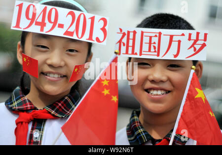 Young Chinese students wave Chinese national flags as they display signs on their foreheads to celebrate the upcoming National Day holidays at a param Stock Photo