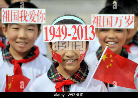 Young Chinese students wave Chinese national flags as they display signs on their foreheads to celebrate the upcoming National Day holidays at a param Stock Photo