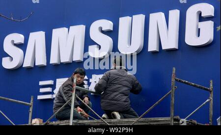 --FILE--Chinese workers install the signage of Samsung at a store in Zhoukou city, central Chinas Henan province, 16 December 2012.   Samsung has succ Stock Photo