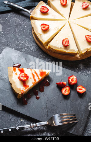 Homemade cheesecake with fresh strawberries sliced on black stone background Stock Photo