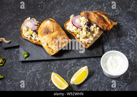 Fish pate, minced herring fillet with apple and egg on toasted rye bread, homemade traditional Jewish cuisine dish forshmak on black stone table Stock Photo