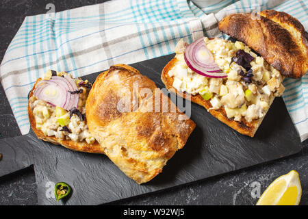 Fish pate, minced herring fillet with apple and egg on toasted rye bread, homemade traditional Jewish cuisine dish forshmak on black stone table Stock Photo