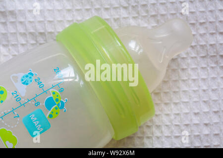 Dirty used Mam baby bottle, baby's bottle, bottle for babies on baby bedding - unhygienic, germs Stock Photo