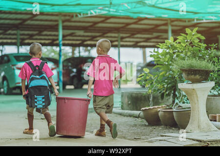 Male Students help to remove rubbish from the classroom to pile waste Stock Photo