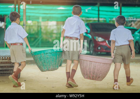 Male Students help to remove rubbish from the classroom to pile waste Stock Photo