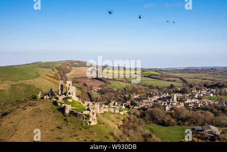 Corfe Castle, England, UK - March 27, 2019: Four military helicopters fly in formation over Corfe Castle village in Dorset.