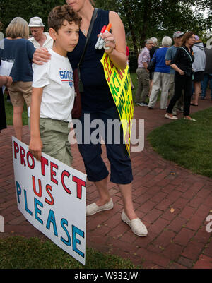 Lexington, MA, USA. 11th Aug, 2019. Enough, Over 100 Lexington residents attended a vigil to end gun violence after U.S. mass gun shootings.  Photo shows Mother holding her son at the end of the vigil. Stock Photo