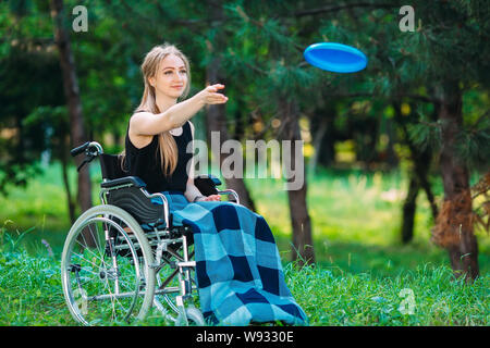 A young disabled girl plays Frisbee with her younger sister. Interaction of a healthy person with a disabled person Stock Photo