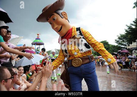--FILE--Tourists shake hands with a figure of Sheriff Woody Pride, or simply Woody, a character in Toy Story produced by Disney, at the Hong Kong Disn Stock Photo