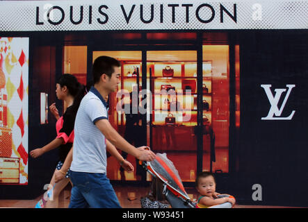 People walk past the Louis Vuitton (LV) boutique at the