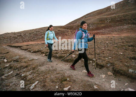 Two young women trail runners enjoy single track trail in the Rockies Stock Photo