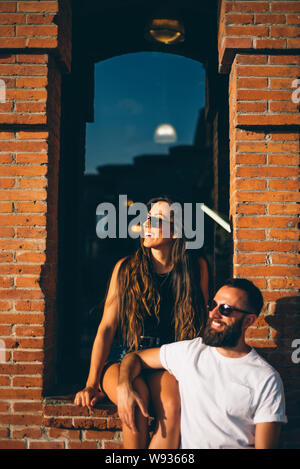 Couple of man and woman posing at sunset with sunglasses. Stock Photo