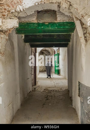 Tetuan, Morocco, Africa - February 15, 2016: Passage in the medina of Tetuan, with an old man on his back walking in the passage