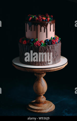 Fruit chocolate cake on wooden stand on black background. Stock Photo