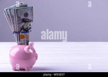 America dollars banknotes money into piggy bank on white background. Saving money wealth and financial concept. Stock Photo