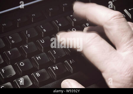 blurred hand typing on a computer keyboard Stock Photo