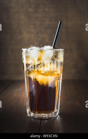 One glass of refreshing drink with ice on dark wooden board. Close up. Vertical shot. Stock Photo
