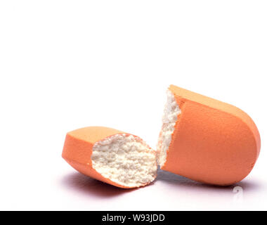 A pill capsule broken into two isolated closeup, addiction, pharmacy monopoly Stock Photo