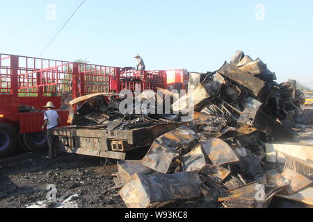 Chinese workers clear away the refrigerators burnt out in the fire on a truck after it collided with an oil tanker on the Huyu (Shanghai-Chongqing) Ex Stock Photo